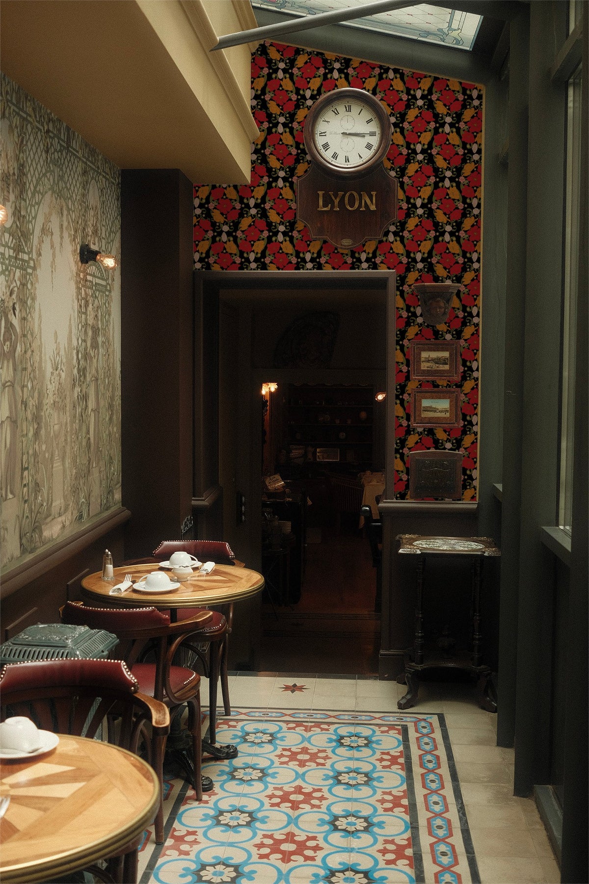 Bloom Noir wallpaper with bold red and orange florals on black in a vintage cafe.