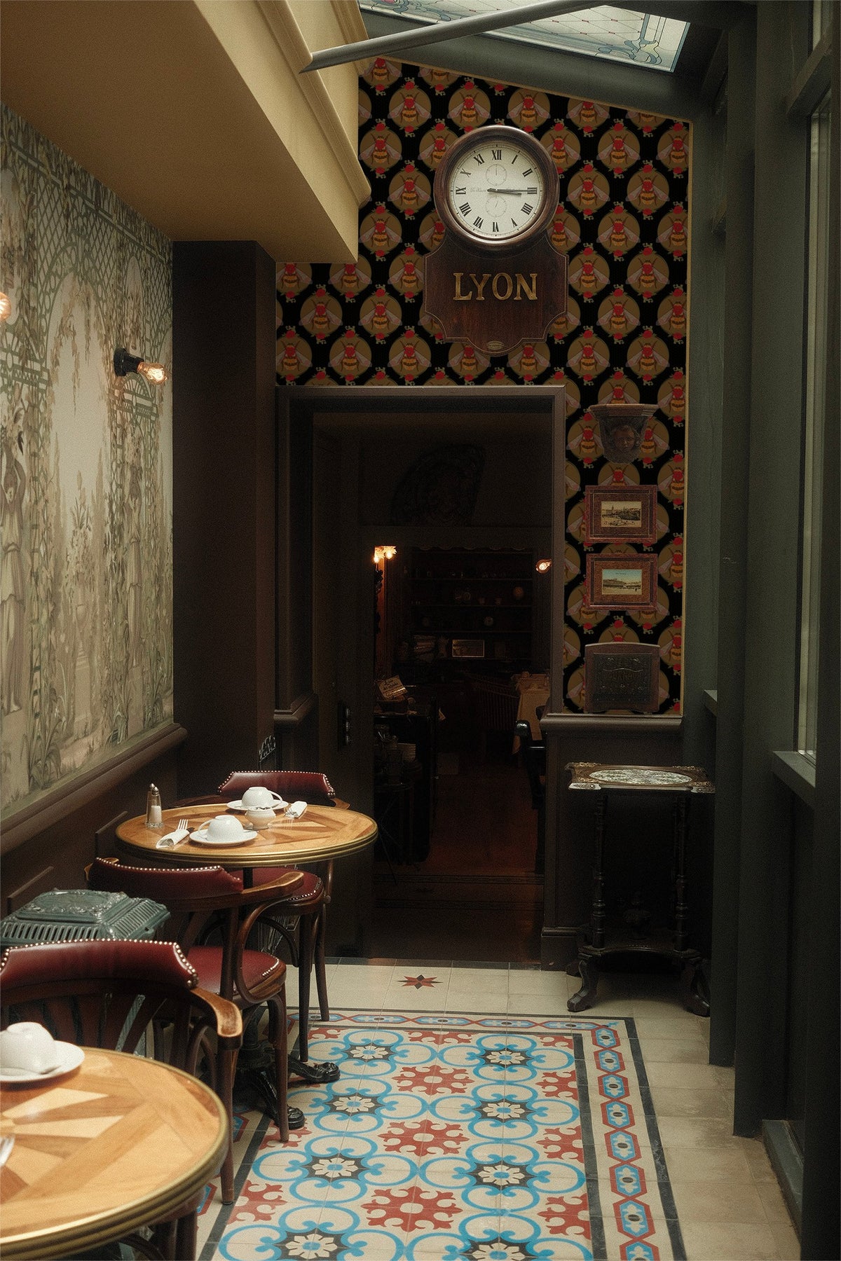 Hive Society Noir wallpaper with bee and floral motifs in vintage cafe setting.